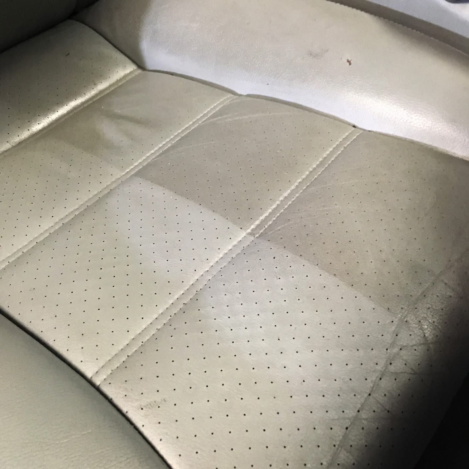 A perforated leather seat partway through cleaning