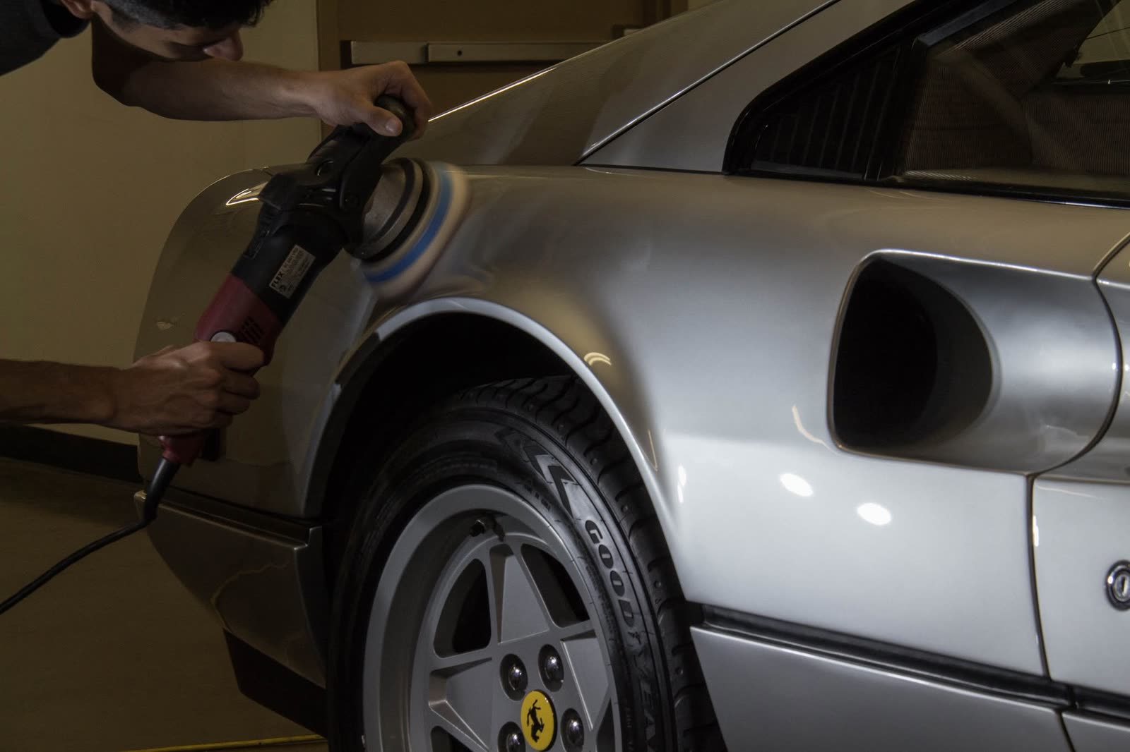 Polishing the rear quarter of a silver Ferrari 308