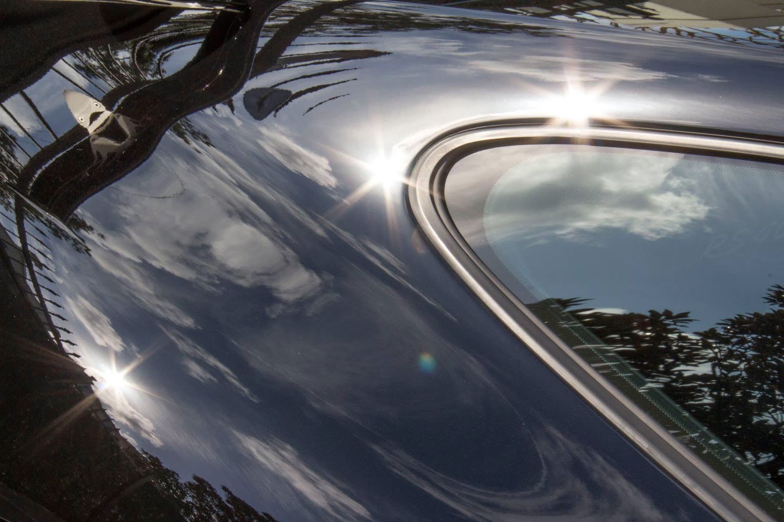 Sun and clouds reflected in the black roofline of a Porsche 911 GT3 RS 4.0