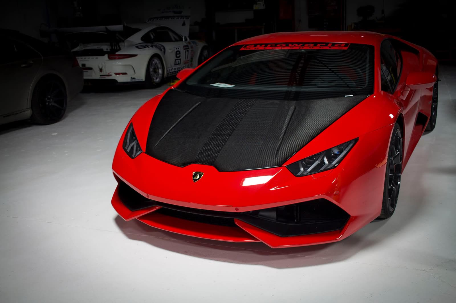 A red Lamborghini Huracán with a carbon fiber hood in the studio
